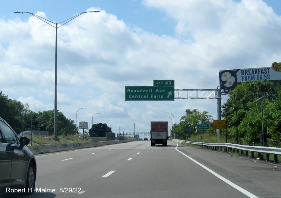 Image of overhead ramp sign for Roosevelt Avenue exit on I-95 South in Attleboro MA with new milepost 
      based exit number and yellow Old Exit 30 advisory sign below, August 2022