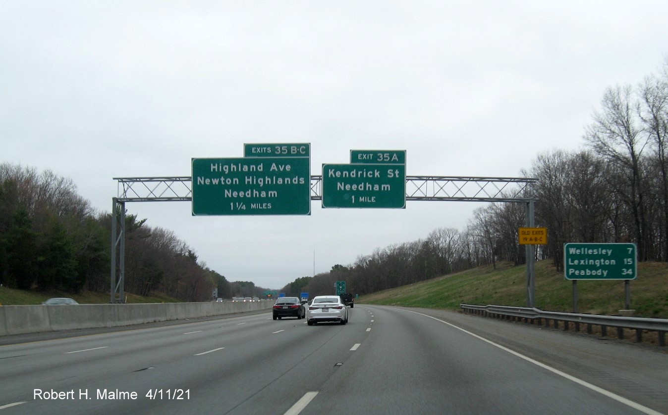 Image of 1 and 1 1/2 Mile advance signs for Kendrick Street and Highland Avenue exits with new milepost 
                                            based exit numbers and yellow Old Exits 19 A-C advisory sign on right support on I-95/MA 128 North in Needham, April 2021