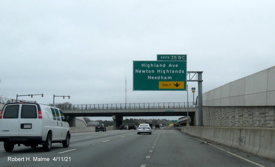 Image of overhead ramp exit only sign for Highland Avenue exits with new milepost 
                                            based exit numbers on I-95/MA 128 North in Needham, April 2021
