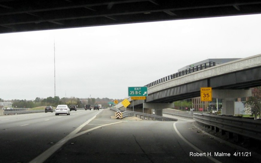 Image of gore sign for Highland Avenue exits with new milepost 
                                            based exit numbers on I-95/MA 128 North in Needham, April 2021