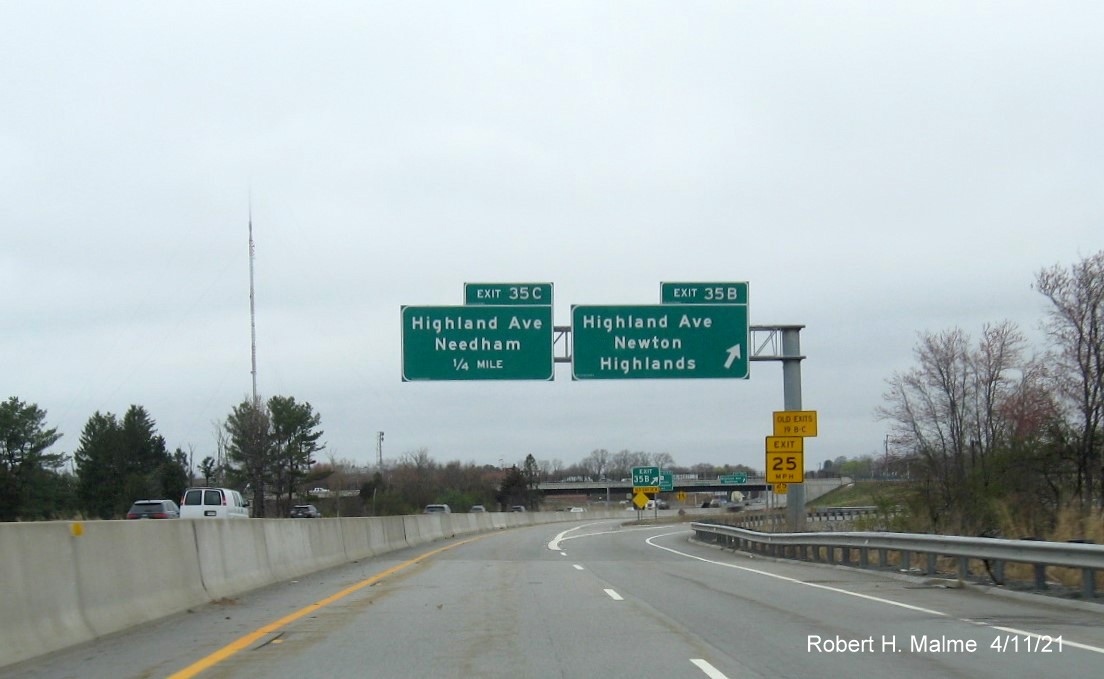 Image of overhead signs at ramp for Highland Avenue East exit with new milepost 
                                            based exit numbers gore sign with new number and yellow Old exit sign below on C/D ramp from I-95/MA 128 North in Needham, April 2021