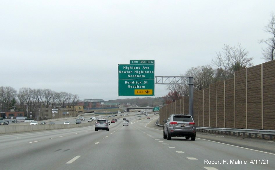 Image of overhead C/D ramp sign for Highland Avenue/Kendrick Street exits with new milepost based 
                                            exit numbers on I-95/MA 128 South in Needham, April 2021