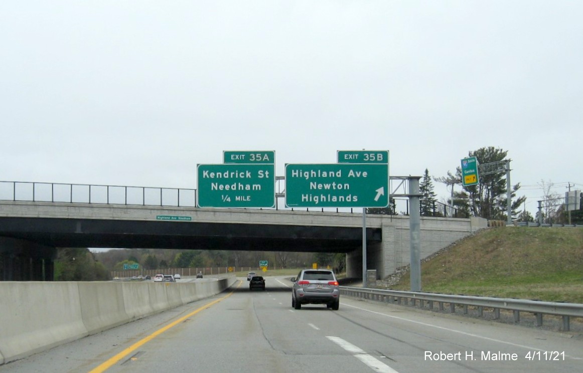 Image of overhhead signs for Highland Avenue East and Kendrick Street exits with new milepost based 
                                            exit numbers on C/D ramp from I-95/MA 128 South in Needham, April 2021