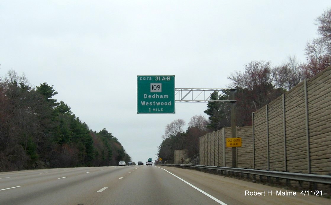 Image of 1 Mile advance overhead sign for MA 109 exits with new milepost based exit numbers and yellow 
                                         Old Exits 16 A-B advisory sign on support on I-95/MA 128 North in Dedham, April 2021