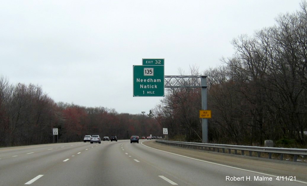 Image of 1 Mile advance overhead sign for MA 135 exit with new milepost based exit number and yellow 
                                           Old Exit 17 advisory sign on support on I-95/MA 128 North in Dedham, April 2021