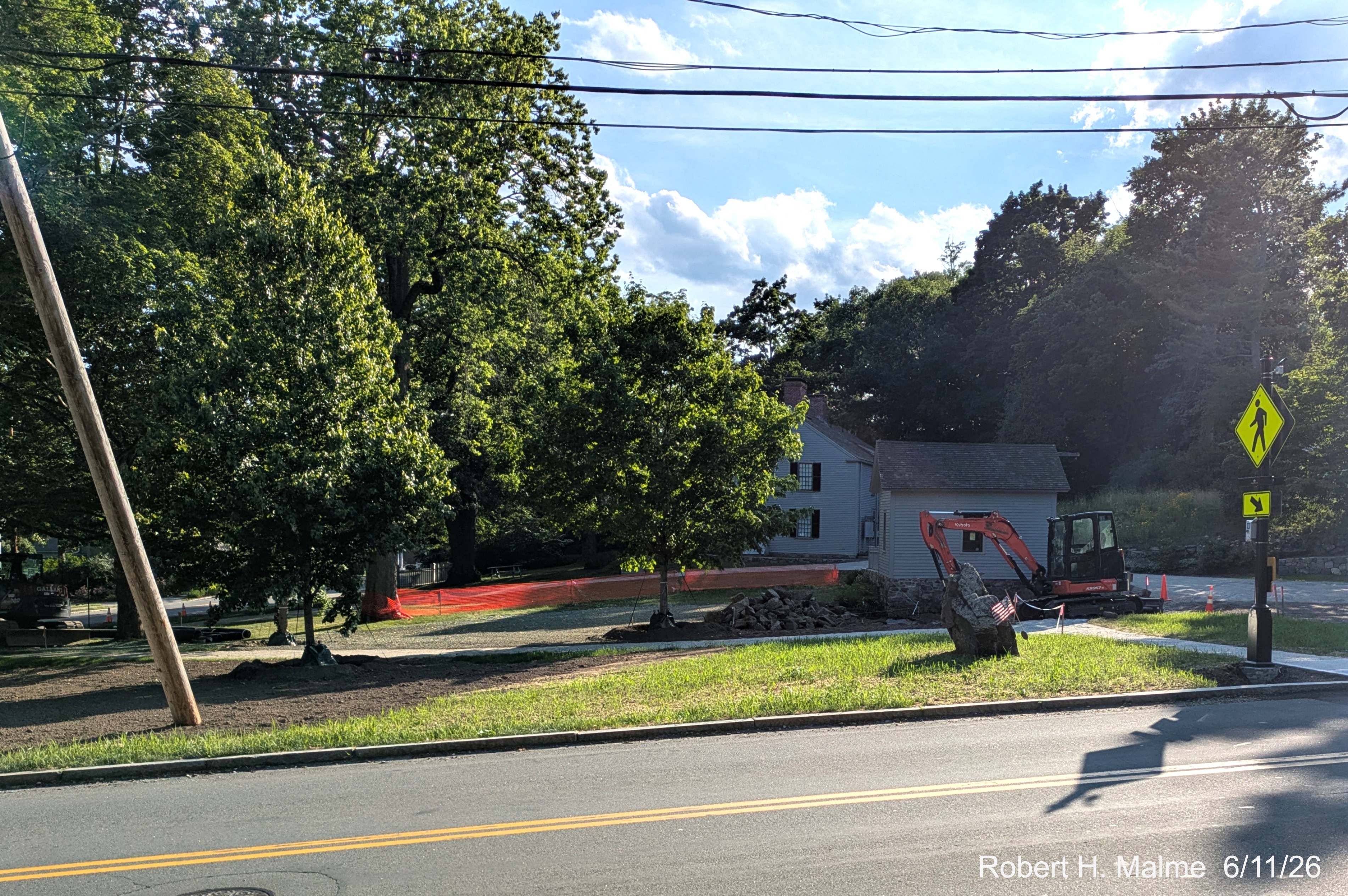 Image of taken along Lincoln Street toward the Benjamin Lincoln House showing work 
	on the rock wall continuing, June 2026