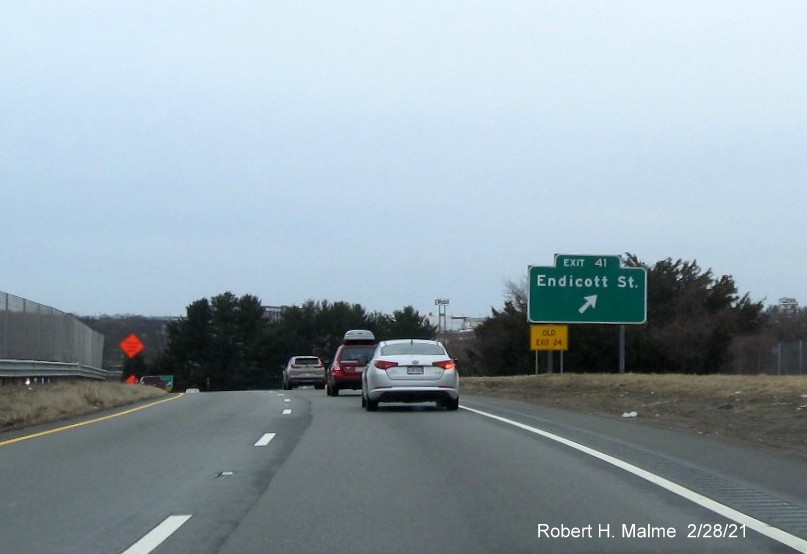 Image of ground mounted ramp sign for the Endicott Street exit with new milepost 
      based exit number and yellow old exit sign in front of the sign on MA 128 South in Danvers, February 2021