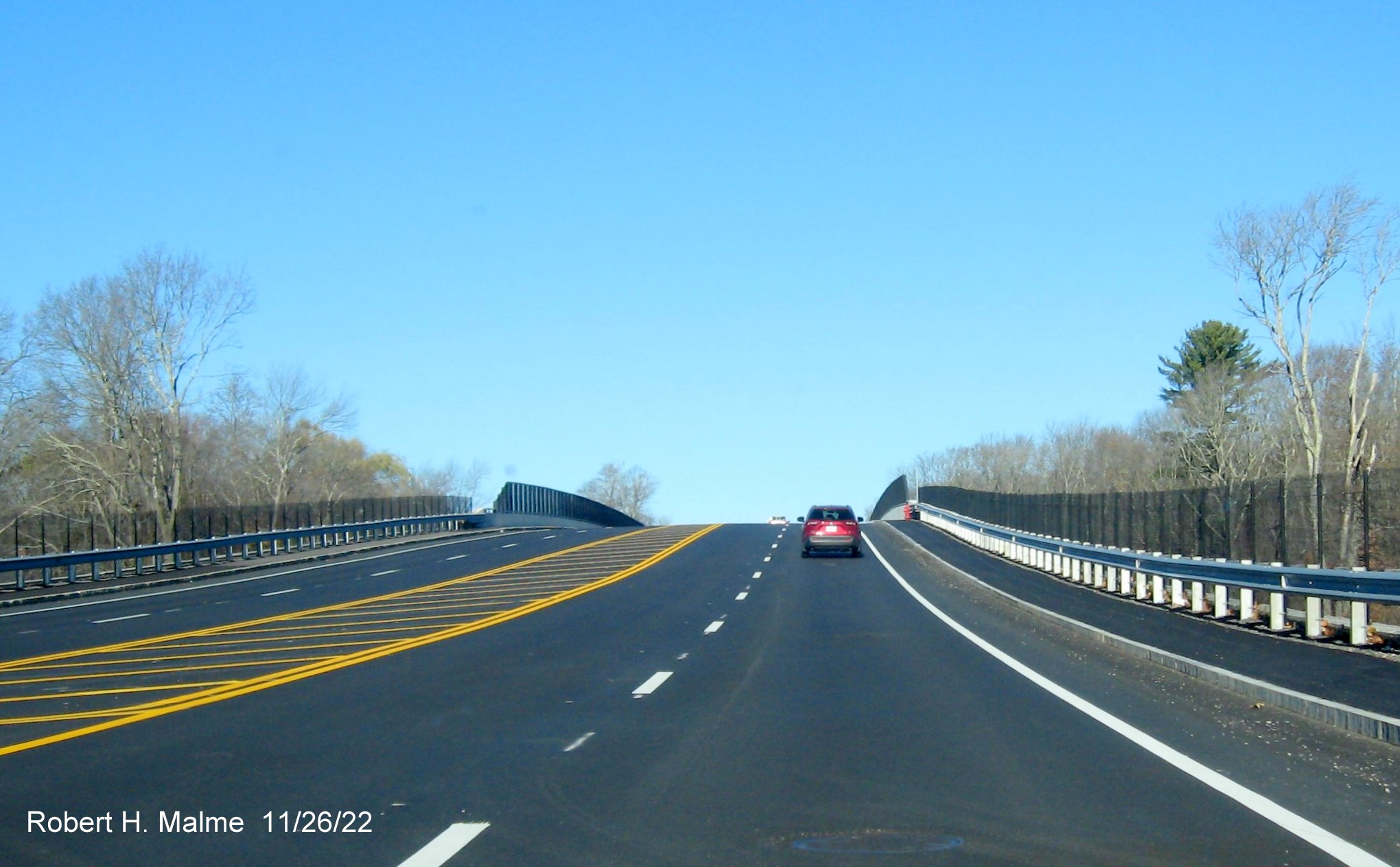 Image of MA 18 traffic heading up completed commuter railroad bridge in South Weymouth, November 2022