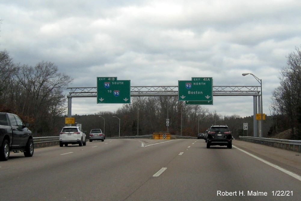 Image of overhead signs for I-93 exits with new milepost based exit number and yellow old exit numbers signs on MA 24 North in Randolph, January 2021