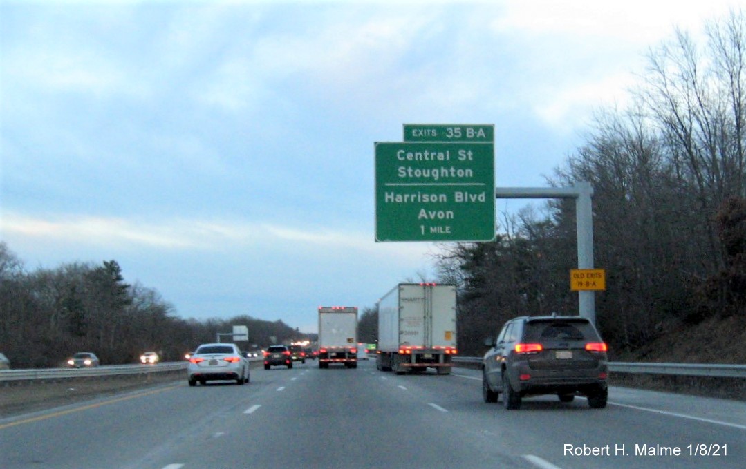 Image of 1 mile advance overhead sign for Central St./Harrison Blvd. exits with new milepost based exit number 
                                      and yellow old exit number sign on support post on MA 24 South in Avon, January 2021