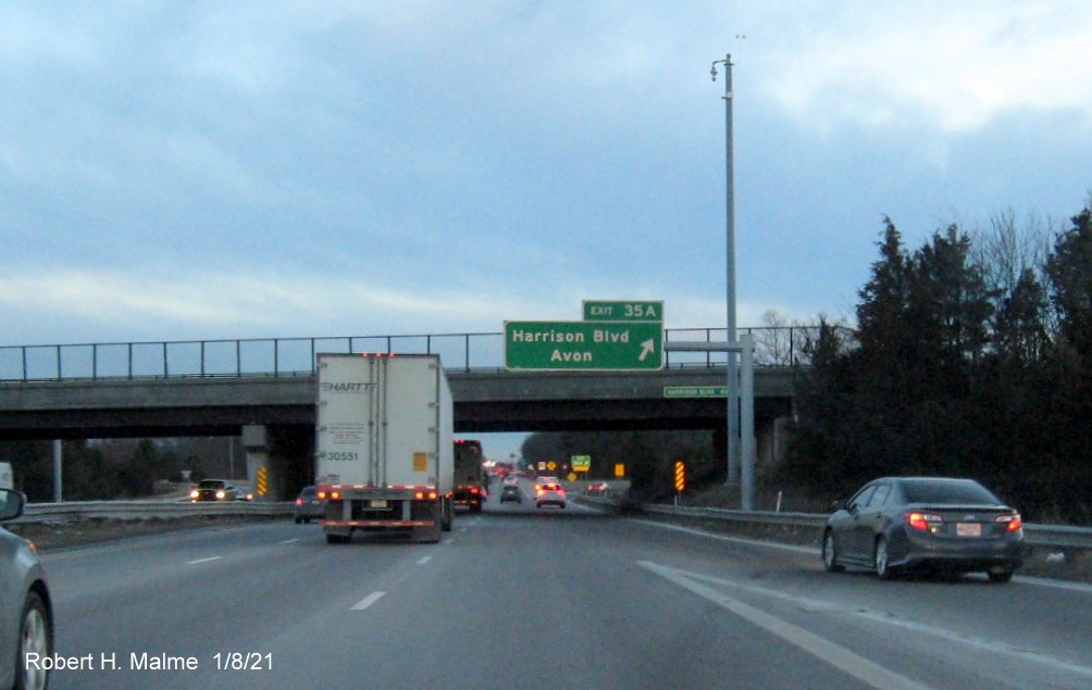Image of overhead ramp sign for Harrison Blvd. exit with new milepost based exit number 
                                      and gore sign with yellow old exit number sign below on MA 24 South in Canton, January 2021