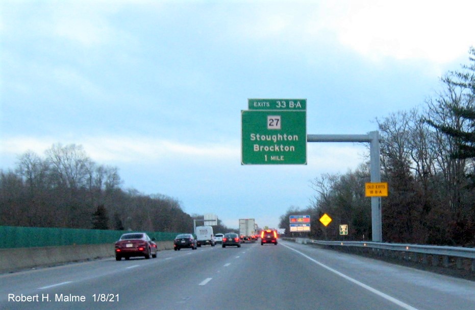 Image of 1 mile advance overhead sign for MA 27 exits with new milepost based exit number 
                                      and yellow old exit number sign on support post on MA 24 South in Brockton, January 2021