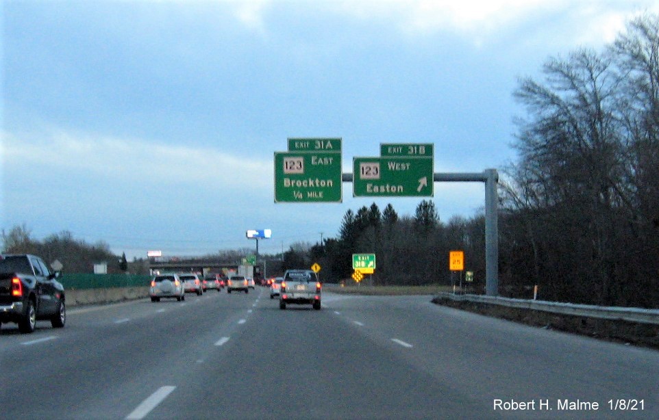 Image of overhead signs at ramp for MA 123 West exit with new milepost based exit number 
                                      and gore sign with yellow old exit number sign below on MA 24 South in Brockton, January 2021