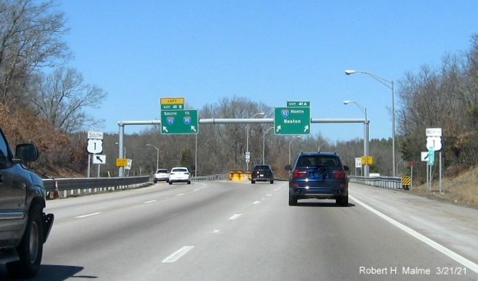 Image of overhead ramp sign recently placed on MA 24 North in Randolph with new milepost based exit numbers and yellow Old Exits 21 B-A advisory sign on right support, March 2021