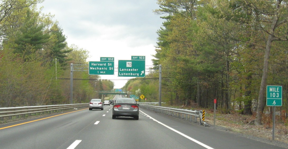 Image of 1 mile advance overhead sign for Mechanic Street exit with new milepost based exit number and yellow Old Exit 34 advisory sign on support on MA 2 East in Leominster, May 2021