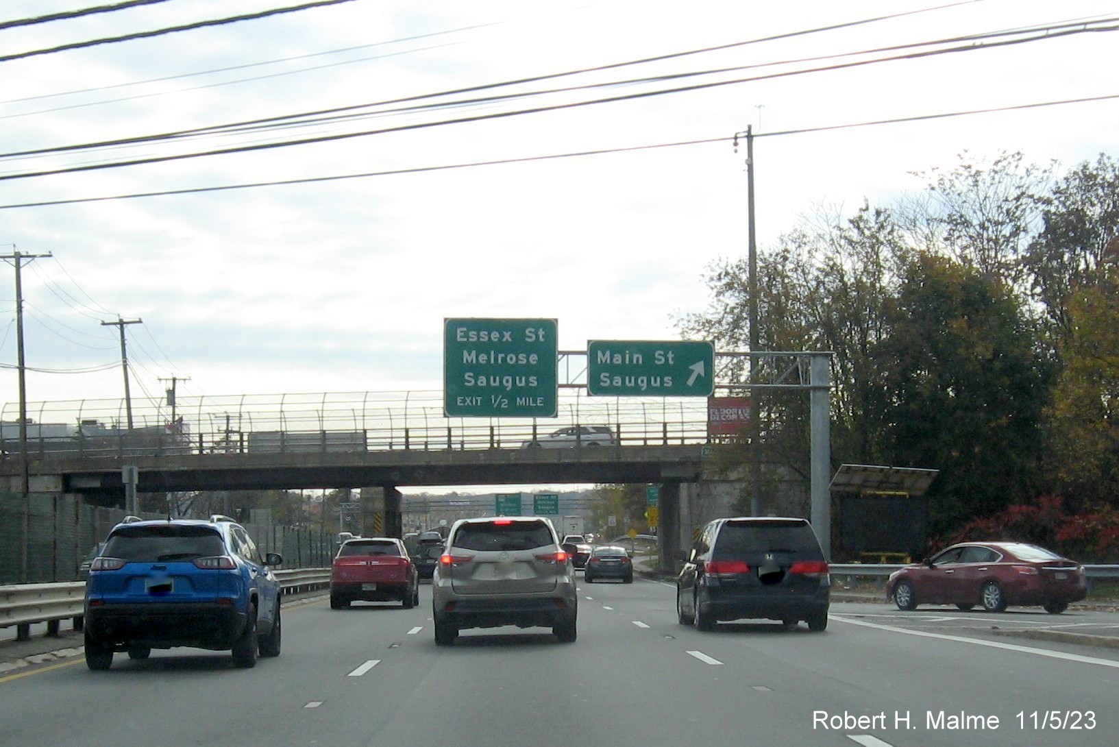 Image of recently placed right side Main Street exit sign and 1/2 mile advance overhead sign for 
        the Essex Street exit on US 1 South in Saugus, November 2023