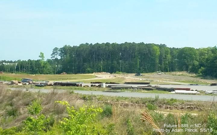 Image of future US 70 freeway lanes from current US 70 roadway, lanes being used as storage area for construction equipment for East End Connector/I-885 project in Durham, by Adam Prince