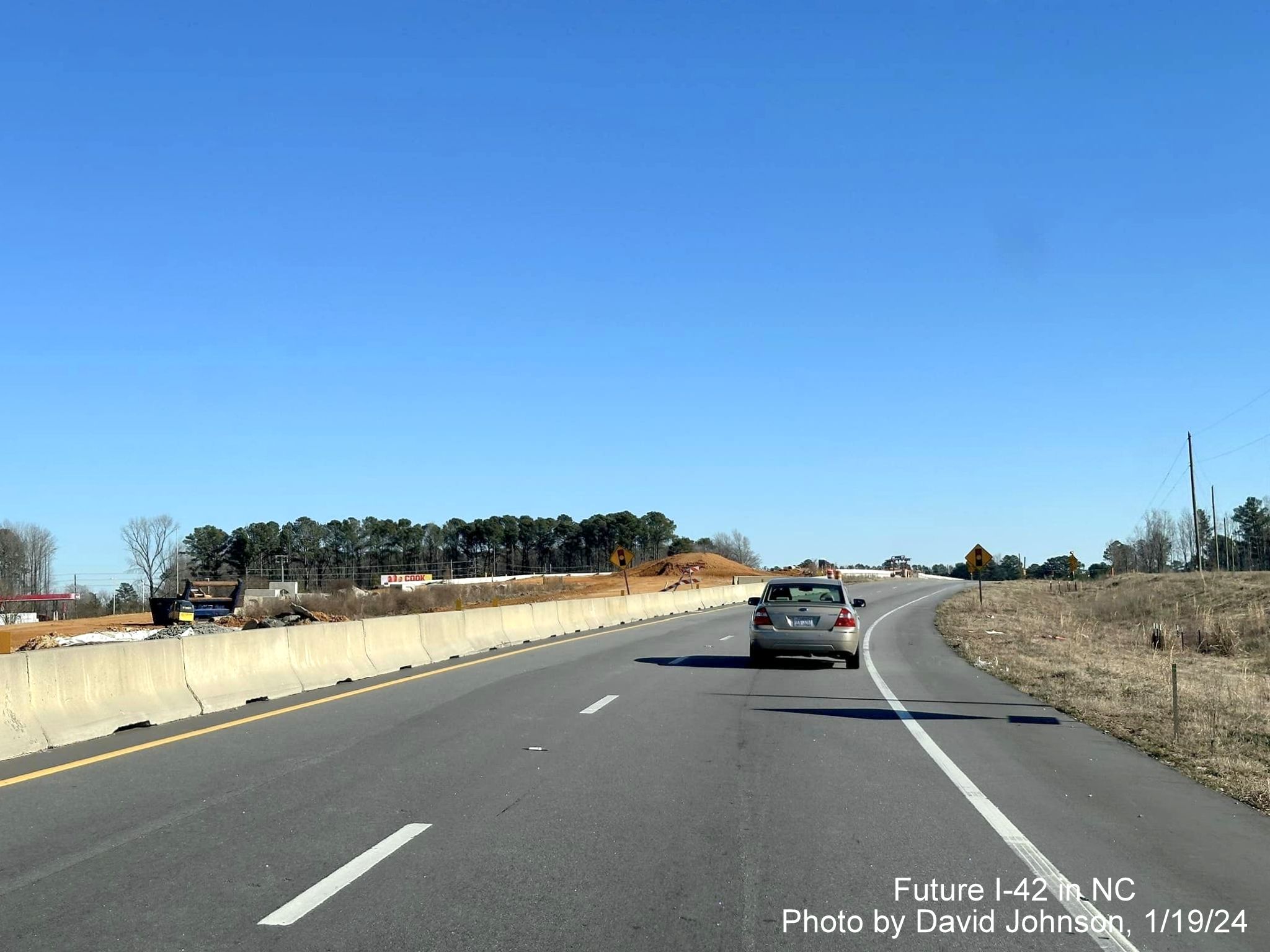 Image of traffic on US 70 East using future exit ramp for Wilson's Mills Road as temporary roadway
through interchange work zone, photo by David Johnson, January 2024