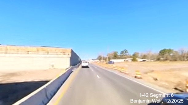 Image of traffic between abutments on US 70 West for bridge to take I-42 over
		Grantham Road, screen grab from Benjamin Wolf video, December 2025