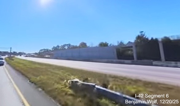 Image of noise wall under construction along US 70 East looking back from the
		westbound lanes prior to the US 17/NC 55 exit on US 70 (Future) I-42 West, screen grab from Benjamin Wolf video, December 2025